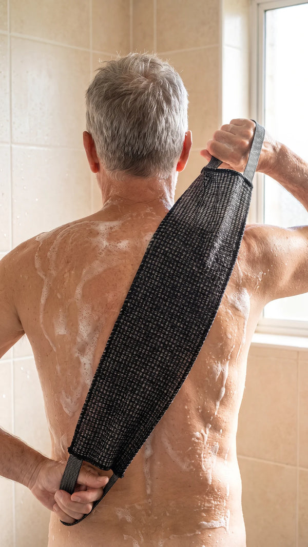 Homme d’une soixantaine d’années qui se frotte le dos avec la serviette exfoliante noire Corpur à poignées