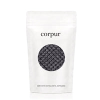 Une serviette de douche exfoliante noire à poignées dans son sachet Corpur