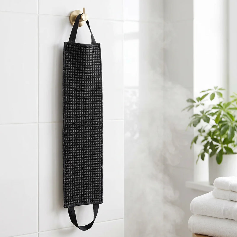 La serviette exfoliante Corpur de 120 cm suspendue par une poignée dans la salle de bain